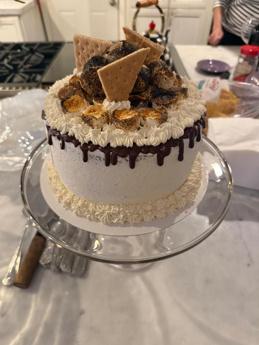 A plant-based s'mores layer cake with toasted marshmallows, graham crackers and a dark chocolate drip